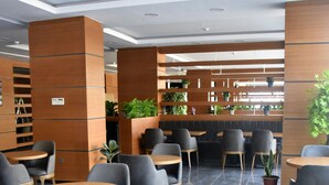 A modern cafe with round tables and grey chairs, featuring a tiled floor and wooden accents.