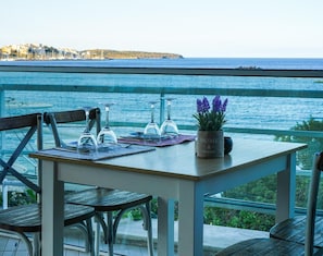A table with a view of the sea, a chair, and a potted plant with purple flowers. - Almiros Apartments (Corfu)