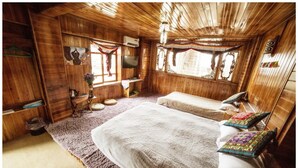 A wooden cabin room with two beds, a TV, and a window with curtains. - Yi's Hostel (Deqin)