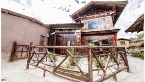A traditional wooden building with a large entrance and a balcony. - Yi's Hostel (Deqin)