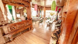 A traditional wooden interior with a wooden dresser, wicker chairs, and a dining table. - Yi's Hostel (Deqin)