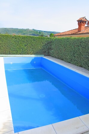 A rectangular swimming pool with a blue interior, surrounded by a low hedge and a tiled deck. - Spacious Villa with a Swimming Pool (Piran)