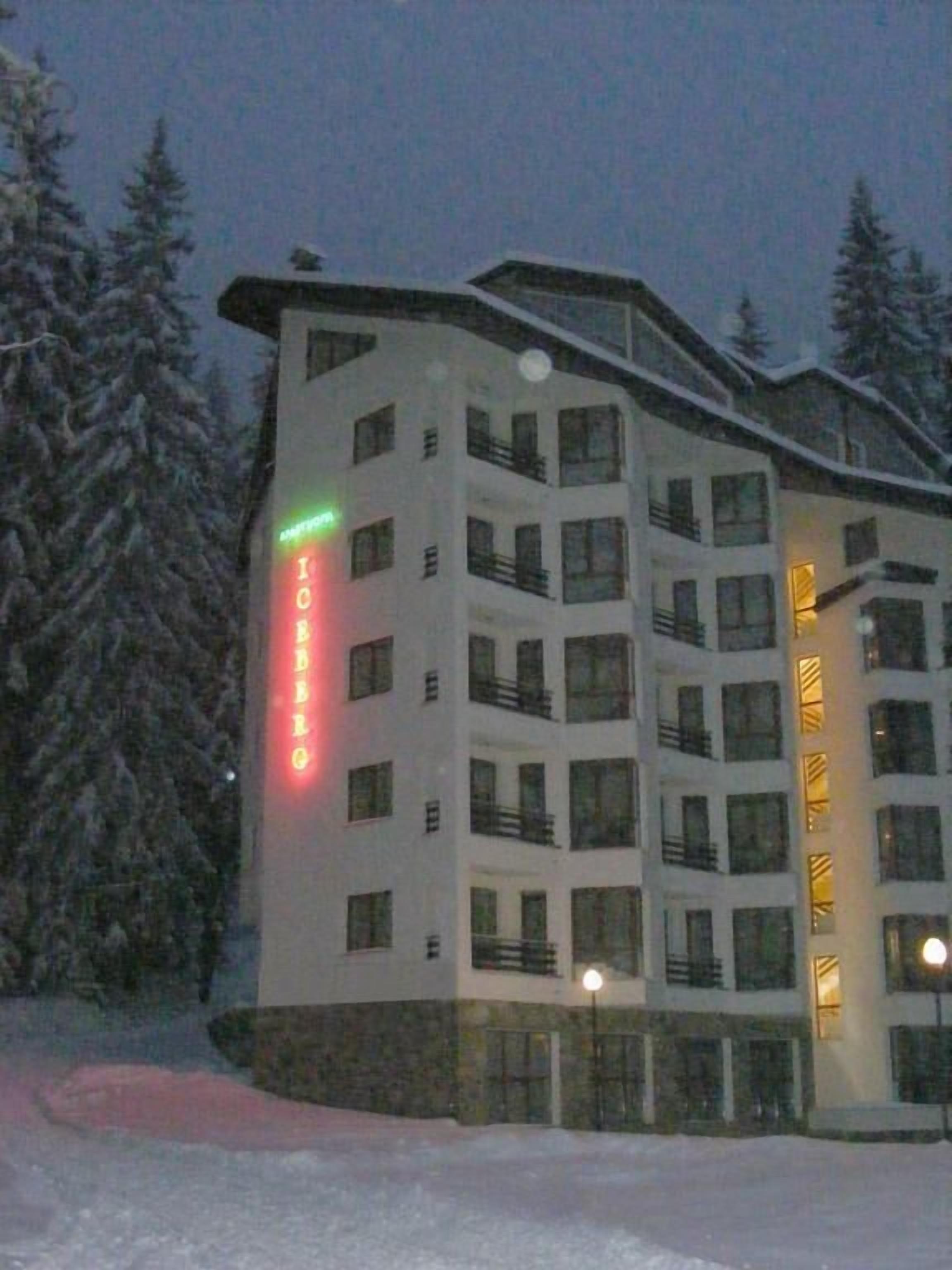 A multi-story hotel with balconies, surrounded by snow-covered trees.