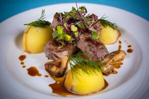 A plate of food with meat, potatoes, and greens. - Dwór Bogucin Hotel & Restauracja (Garbow)