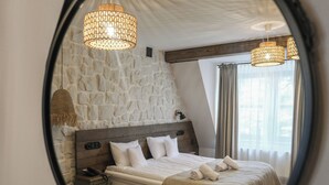 A bedroom with a stone wall, a wooden headboard, a bed with white linens, and two hanging light fixtures. - Dwór Bogucin Hotel & Restauracja (Garbow)