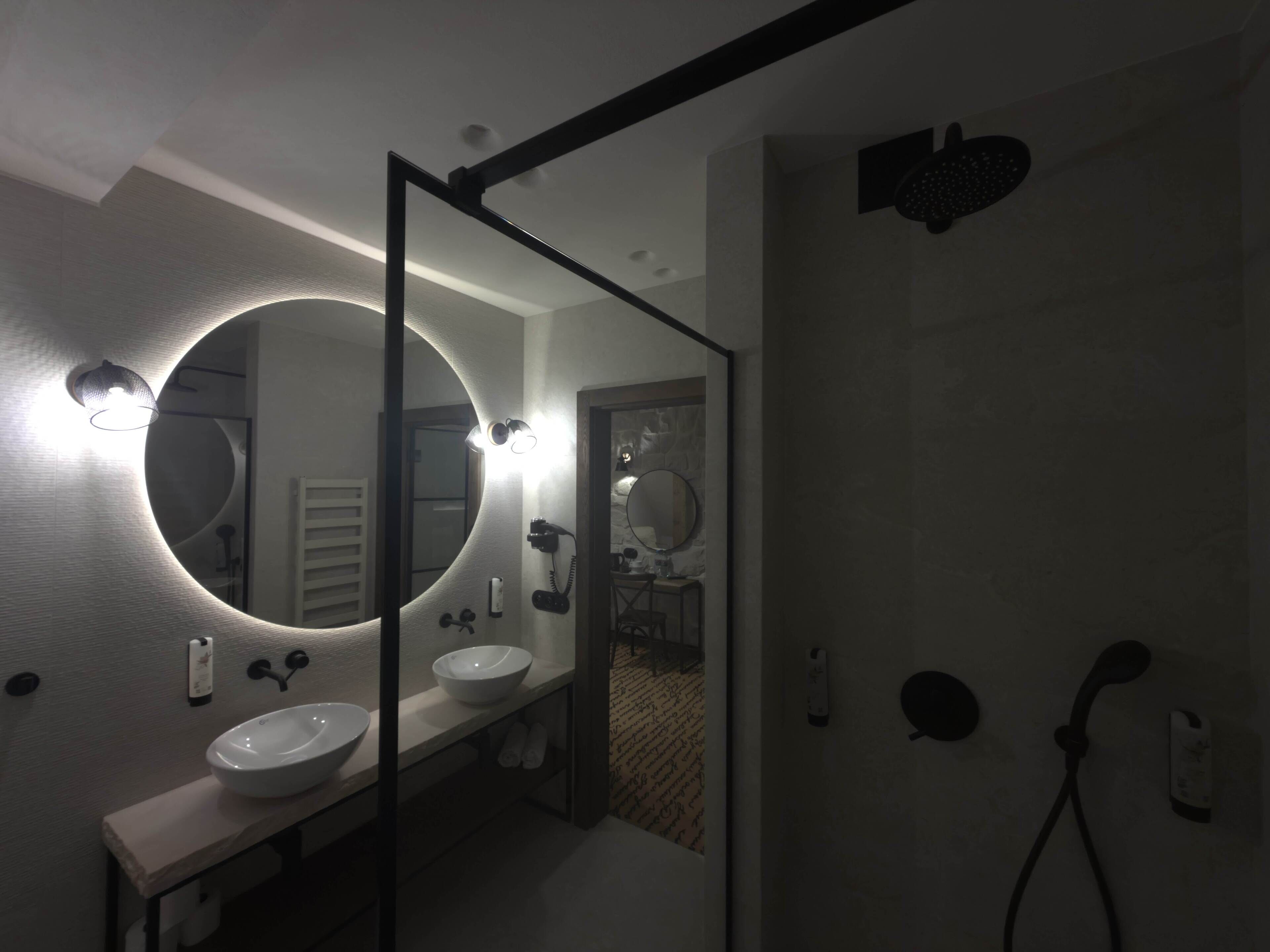 Ein modernes Badezimmer mit zwei Waschbecken, einem großen Spiegel und einer Dusche.