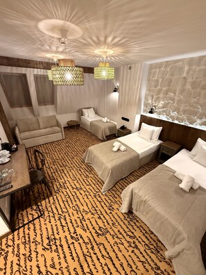 A hotel room with two beds, a sofa, a small table with cups and glasses, and a patterned carpet. - Dwór Bogucin Hotel & Restauracja (Garbow)