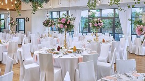 A banquet hall with round tables set for dining, white chairs, and floral centerpieces. - Dwór Bogucin Hotel & Restauracja (Garbow)