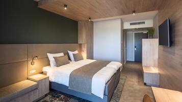 Een moderne slaapkamer met een groot bed, nachtkastjes, een televisie en een houten hoofdbord.