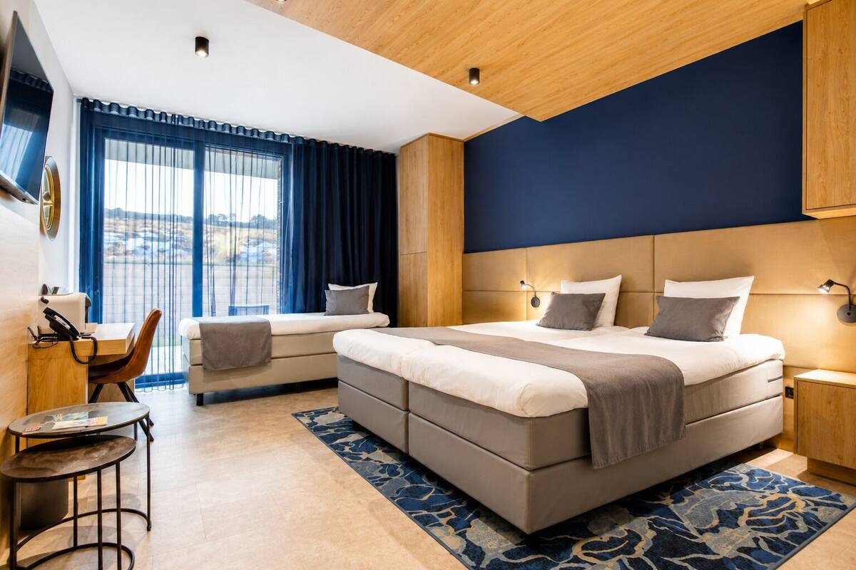 Moderni hotellihuone, jossa on suuri sänky, työpöytä ja näkymä ulos.