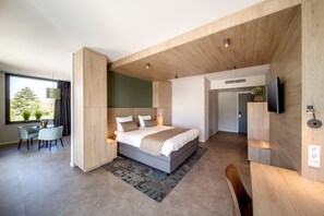 A modern bedroom with a large bed, a desk, and a TV mounted on the wall. - Hotel 46 (Wintelre)