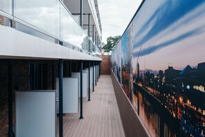 A corridor with a modern design, featuring a glass wall on one side and a mural on the other.