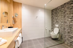 A modern bathroom with a wooden vanity, a glass shower enclosure, and a tiled floor. - Hotel 46 (Wintelre)