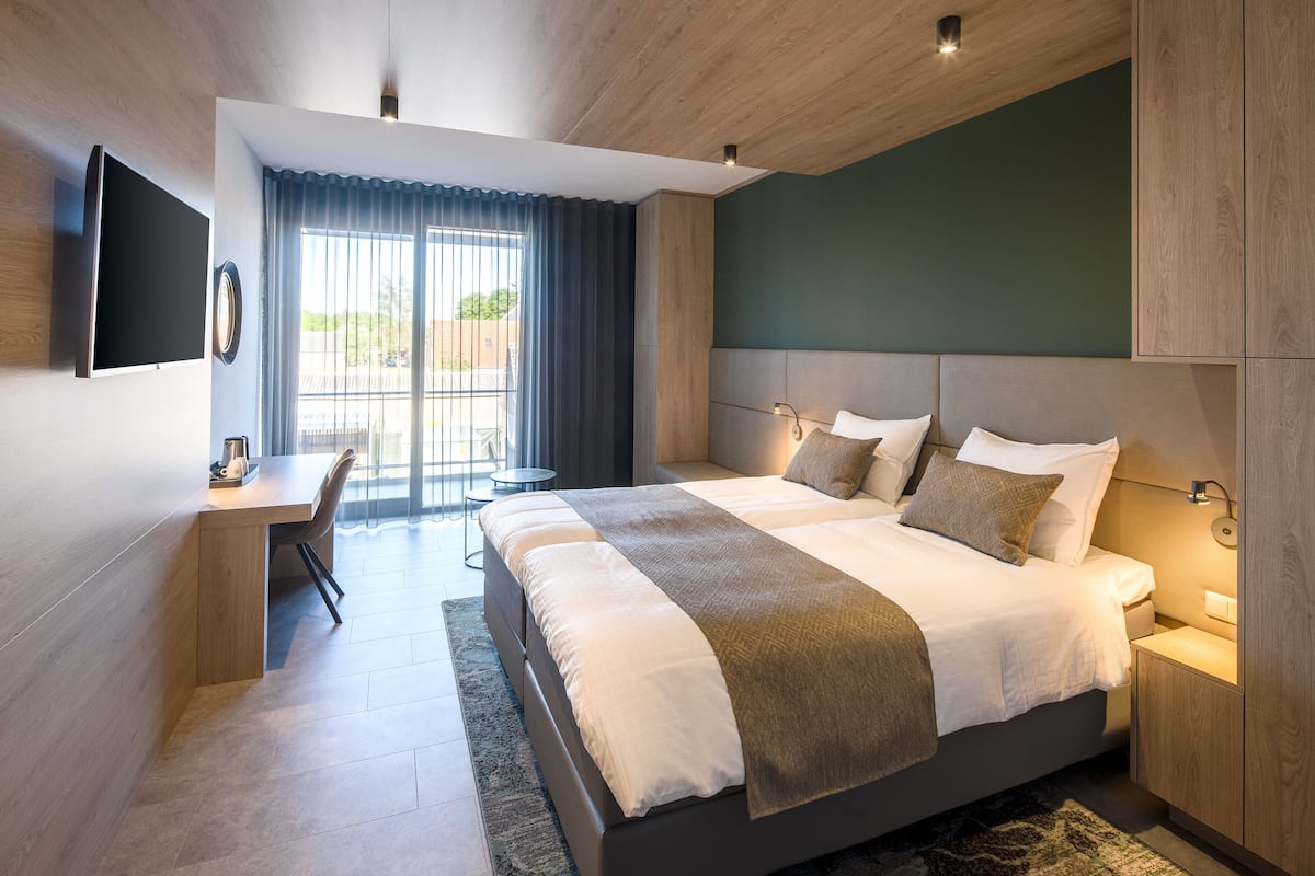 Moderni hotellihuone, jossa on suuri sänky, työpöytä ja televisio.