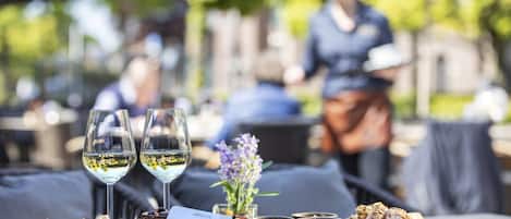 A table with a charcuterie board, two glasses of white wine, and a small vase with purple flowers.