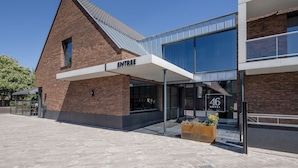 A hotel entrance with a modern design, featuring a brick facade and large glass windows. - Hotel 46 (Wintelre)