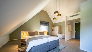 A modern bedroom with a large bed, a walk-in closet, and a bathroom with a bathtub. - Hotel 46 (Wintelre)