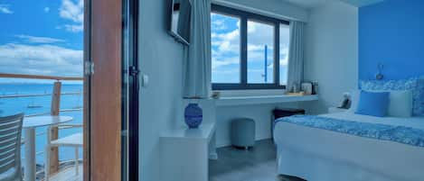 Un dormitorio moderno con una cama grande, un escritorio y vista al mar.