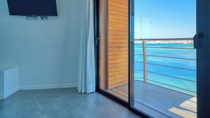 A room with a large TV mounted on the wall, a sliding glass door leading to a balcony with a view of the ocean. - Hotel Boutique La Marquesina - Adults Only (La Oliva)