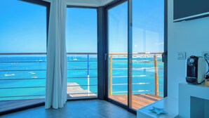 A balcony with a view of the sea and boats, a coffee machine, and a modern interior design. - Hotel Boutique La Marquesina - Adults Only (La Oliva)