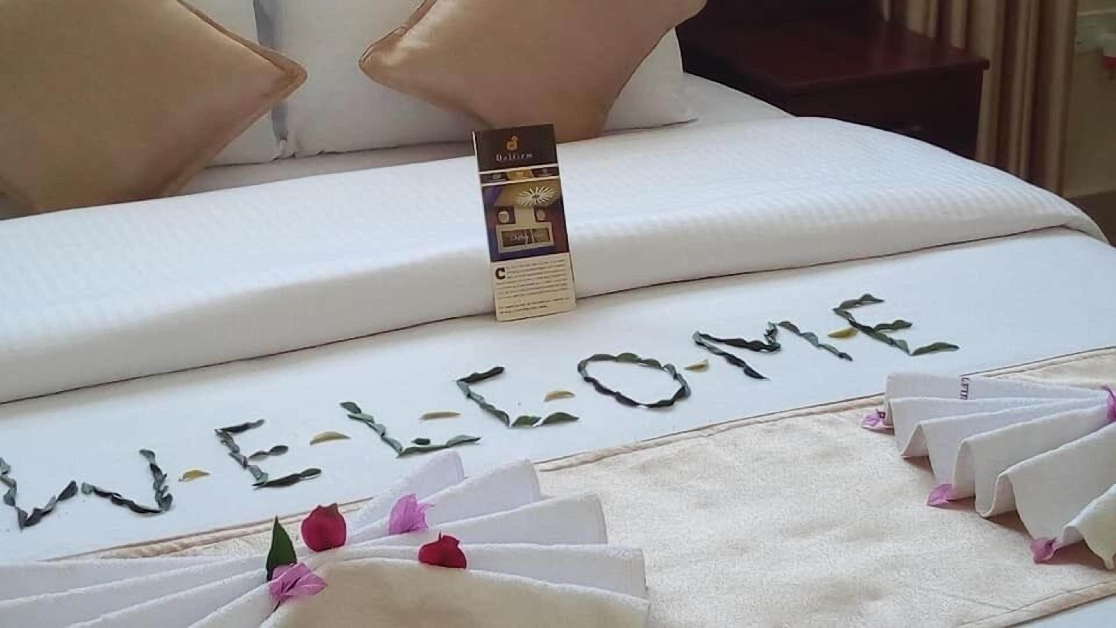 Una cama con un tapete de bienvenida y detalles decorativos.