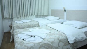 Une chambre d’hôtel avec deux lits, chacun recouvert d’une couvre-lit à motifs et doté d’oreillers blancs.