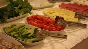 Un buffet proposant une variété d’aliments, notamment des concombres en tranches, des tomates, du fromage et des légumes verts.