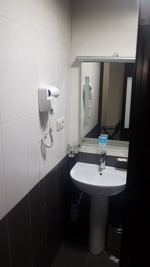 Un bany amb un mànec blanc, un assecador i un mirall.