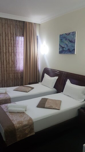 Habitació d'hotel amb dos llits, un quadre a la paret i una finestra amb cortines.