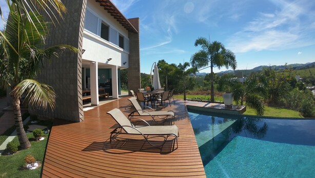 Una casa moderna con piscina, mobiliario exterior y vistas al campo.