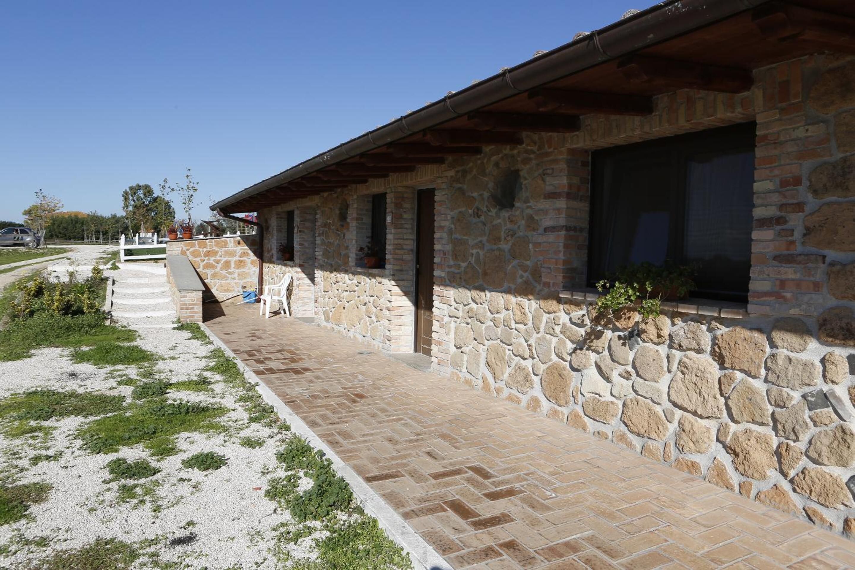 Un bâtiment en pierre doté d’un porche couvert et d’un chemin de gravier.