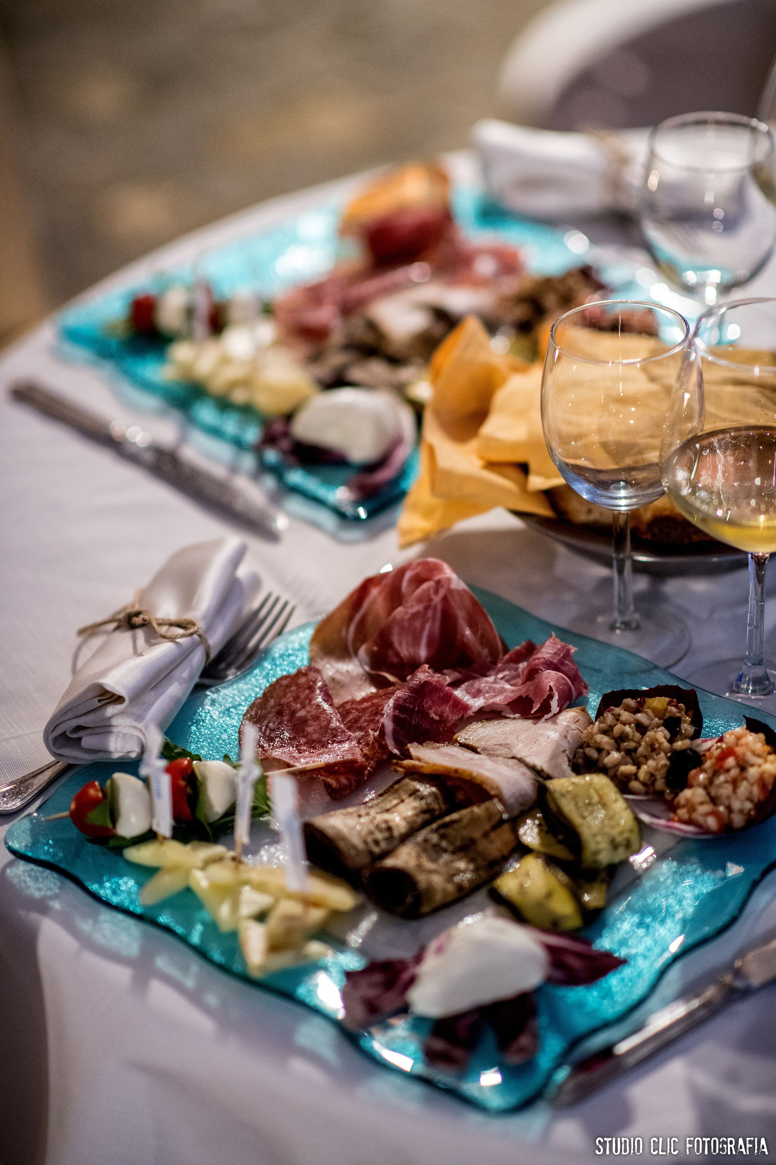 A table set with various dishes, glasses of wine, and neatly folded napkins.