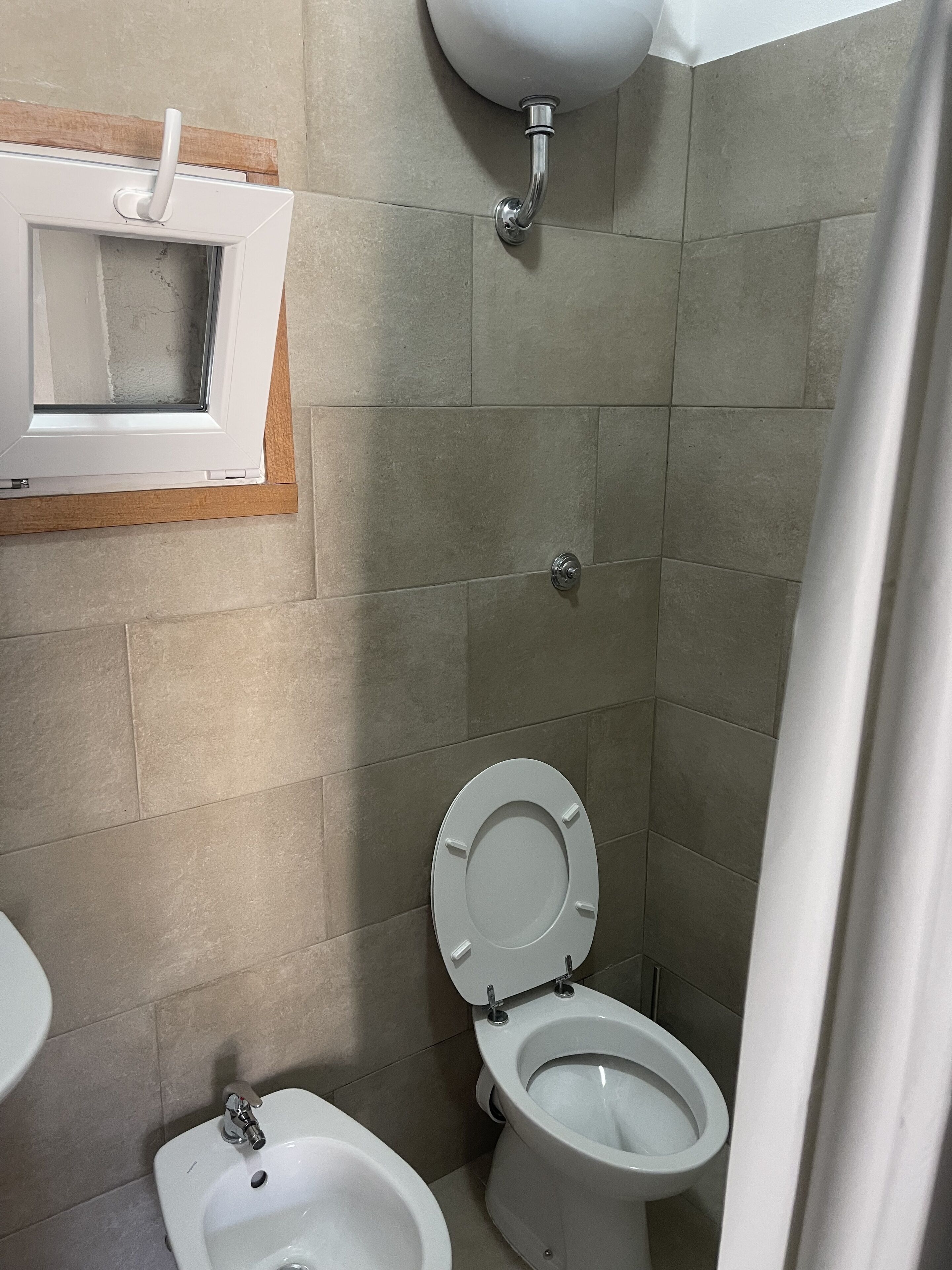 A bathroom with a toilet, bidet, and a sink.