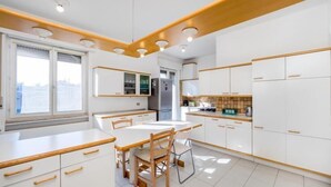Una cocina moderna con armarios blancos, una mesa de comedor y vistas a la ciudad a través de amplias ventanas.