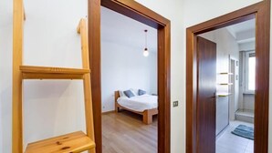 Un dormitorio con una cama, un estante de madera y un pasillo que conduce a un baño.