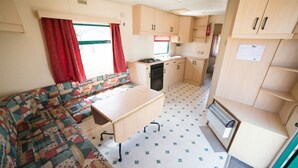A compact RV interior with a kitchenette, a dining area, and a sofa. - Pont de Fournil - Mobil-home (Saint-Laurent-des-Hommes)