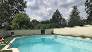 A rectangular swimming pool with a tiled edge, surrounded by a low white wall and a grassy area. - Pont de Fournil - Mobil-home (Saint-Laurent-des-Hommes)
