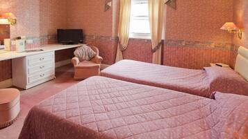 A bedroom with two beds, a desk, and a chair.