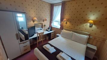 Una habitación de hotel con cama, escritorio, silla y armario.