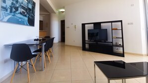 Una sala de estar moderna con comedor, un mueble de TV negro y un cuadro grande en la pared.