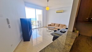 Una cocina moderna con una isla grande, un comedor con sofá y vistas al océano por una puerta corrediza.