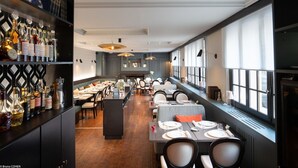 Un restaurante con una barra larga, varias mesas y una zona de bar con botellas.