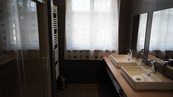 Un baño moderno con dos lavamanos, un espejo grande y una zona de ducha.