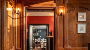 Un pasillo con piso a cuadros, paneles de madera y una mesa redonda con una silla.