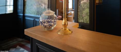 A wooden counter with a brass sign reading "CAISSE" and a glass jar filled with blue and white items.
