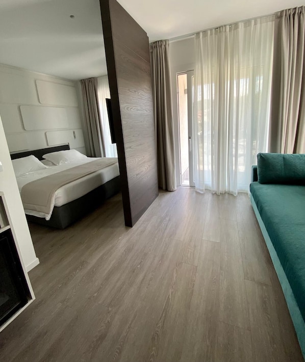Une chambre d’hôtel moderne, équipée d’un lit, d’un canapé et d’une grande fenêtre avec des rideaux.
