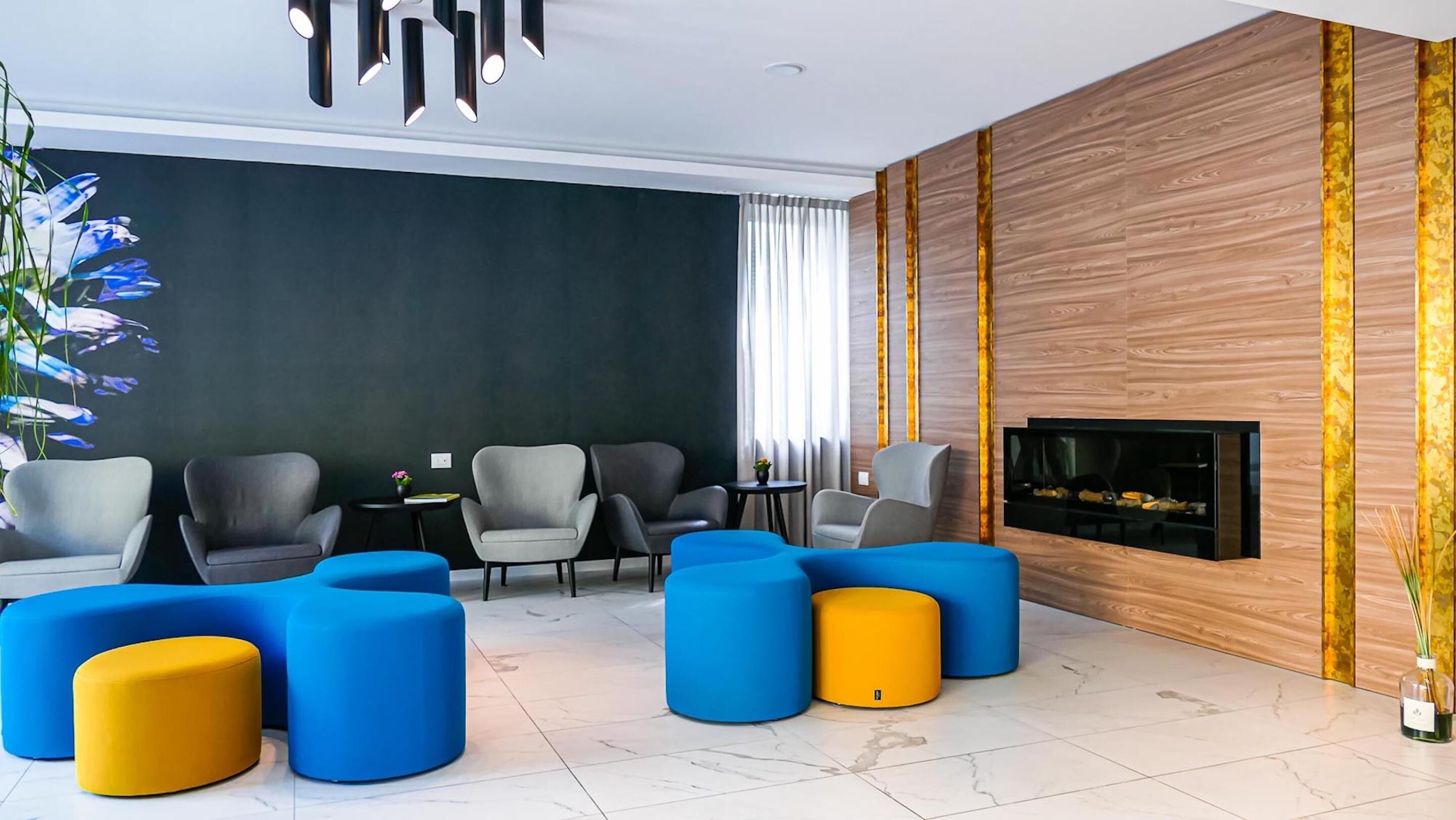 Una sala de estar moderna con chimenea, paredes verde oscuro y un panel decorativo de madera.