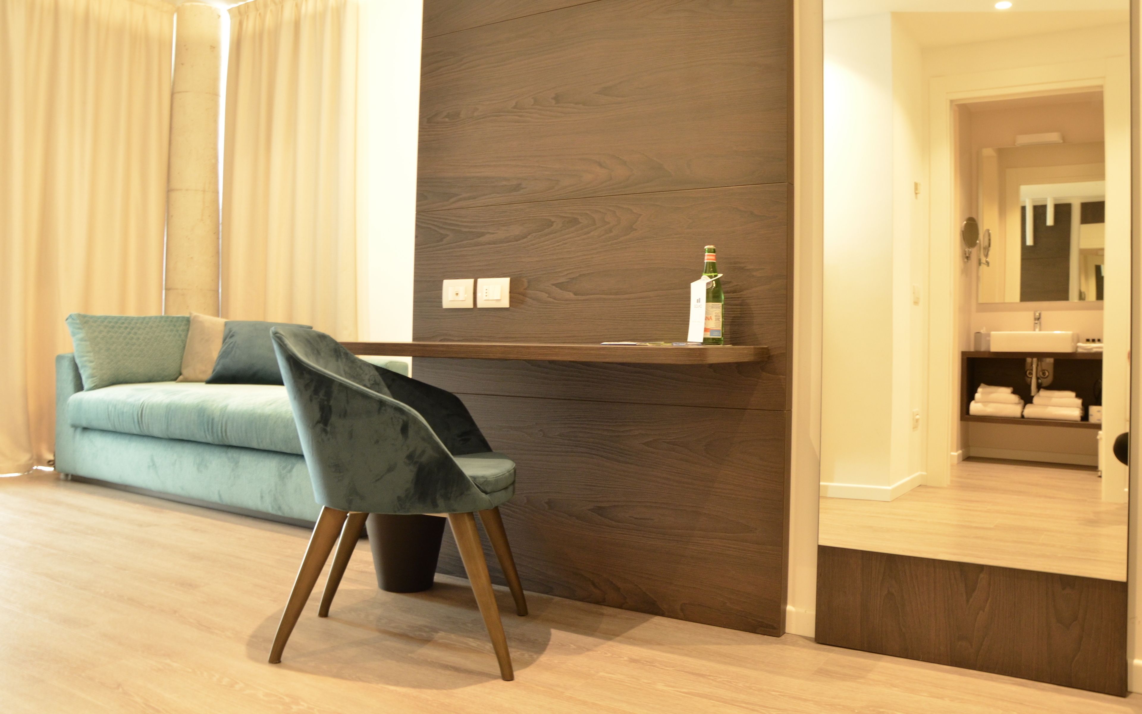 Una sala de estar moderna con un sofá color turquesa, un sillón oscuro y una pared de acento de madera.