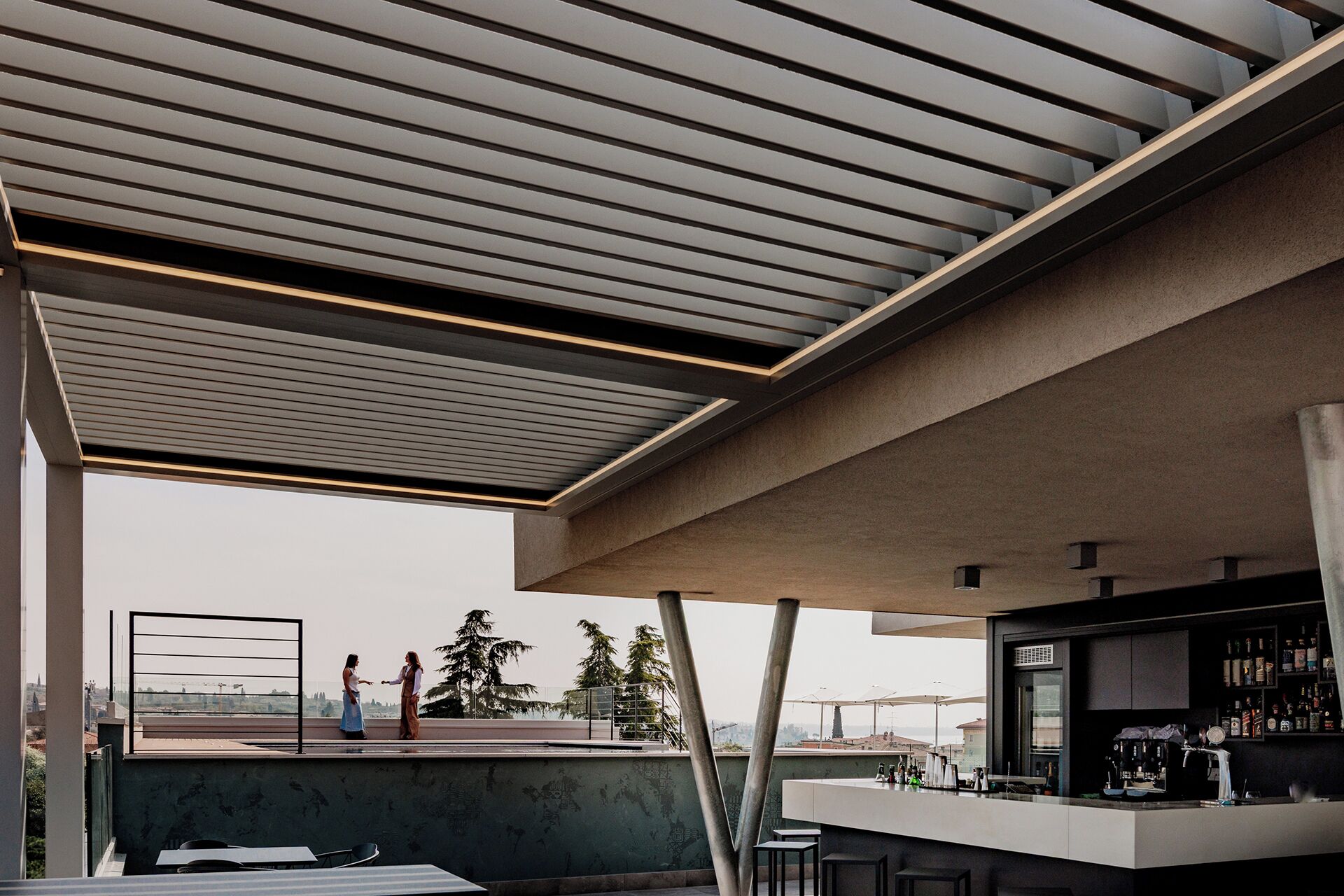 A rooftop bar with a modern design, featuring a bar counter and seating area.