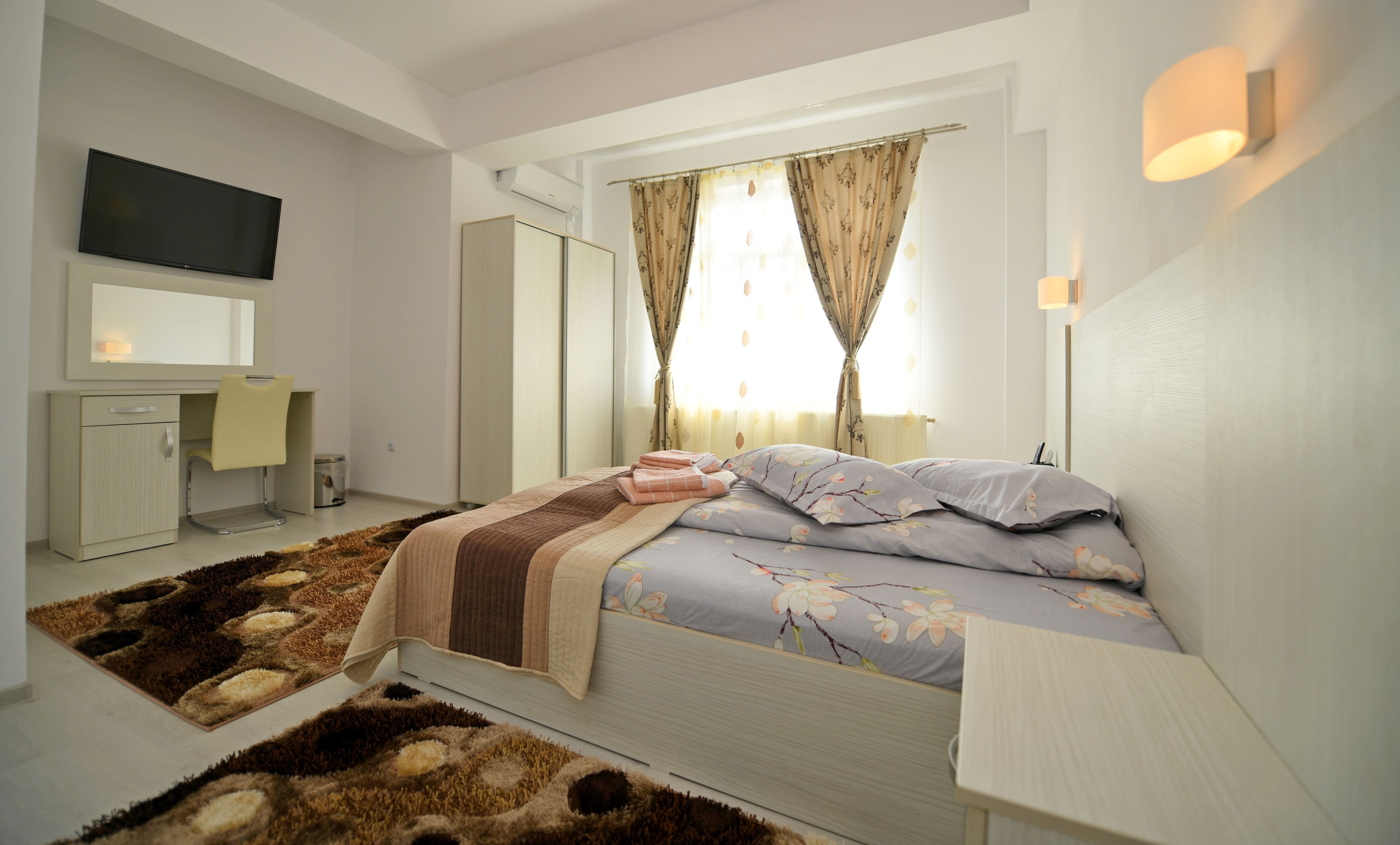 A modern bedroom with a bed, bedside table, and a desk with a chair.